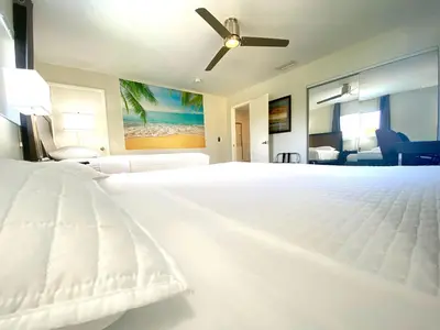 a bedroom with a white bed with a ceiling fan at Tarpon Harbor 1 - Waterfront pool home near beach & downtown Las Olas in Fort Lauderdale