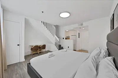 a white bedroom with a bed and a staircase at Sunny Miami Beach Retreat in Miami Beach