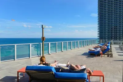 a group of people laying on lounge chairs on the beach at Gorgeous Views Await in Your Beachfront Condo in Hollywood