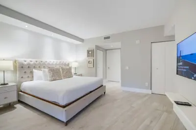 a white bedroom with a large bed and a flat screen tv at Luxury Condo with Oceanfront View in Hollywood in Hollywood