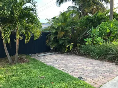 a garden with palm trees and a brick walkway at Calypso Inn Wilton Gay Male Resort in Fort Lauderdale