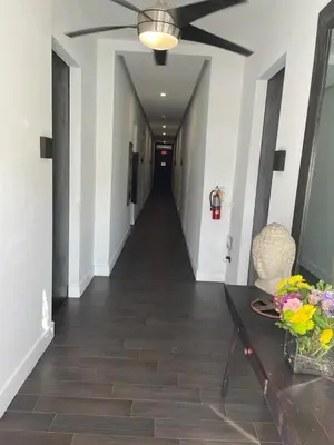 a hallway with a ceiling fan and a table with flowers at Vive Zen Queen Room in Miami