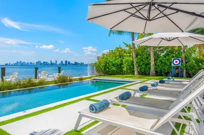 a row of chairs and an umbrella next to a swimming pool at Best Bayfront View New construction w pool in Miami Beach