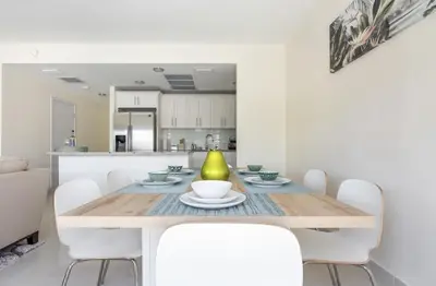 a dining room with a table and white chairs at Modern Townhouse with terrace! in Homestead
