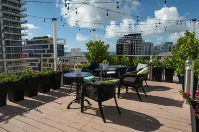 a patio with tables and chairs on a roof at Hotel Croydon in Miami Beach