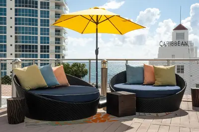 two chairs and an umbrella sitting on a balcony at Hotel Croydon in Miami Beach