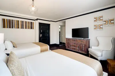 a hotel room with two beds and a flat screen tv at Hotel Croydon in Miami Beach