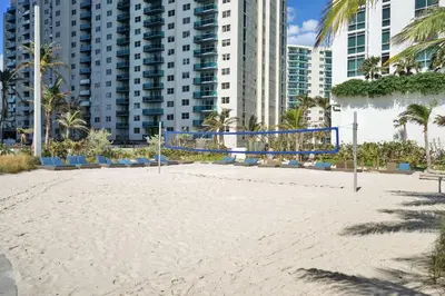 a volleyball court on the beach in front of buildings at Oceanfront Condo Direct Ocean & Beach Club Access in Hollywood