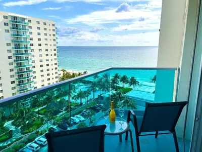 a balcony with a table and chairs and the ocean at Ocean View Modern Condo Beach Access 11M in Hollywood