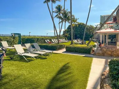 a lawn with lounge chairs and palm trees and a house at 3 Bedroom Apt Ocean-Front Resort The Alexander in Miami Beach