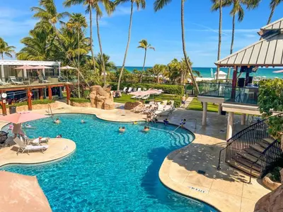 a pool at a resort with palm trees and the ocean at 3 Bedroom Apt Ocean-Front Resort The Alexander in Miami Beach