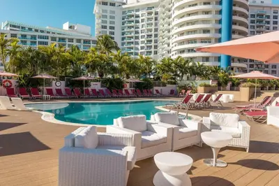 a swimming pool with white chairs and tables and a swimming pool at 3 Bedroom Apt Ocean-Front Resort The Alexander in Miami Beach