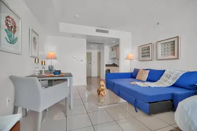 a living room with a blue couch and a table at Beautiful Blue & Gold Studio With Ocean View in Miami