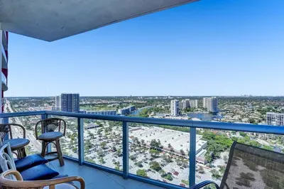 a balcony with chairs and a view of a city at Sky-High Spacious Ocean View Condo 4 BDRS 3 BATH in Hallandale Beach