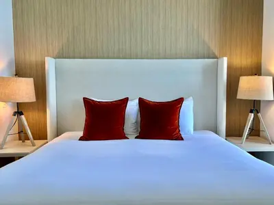 a white bed with two red pillows and two lamps at Direct Oceanfront Condo - Hyde Resort in Hollywood