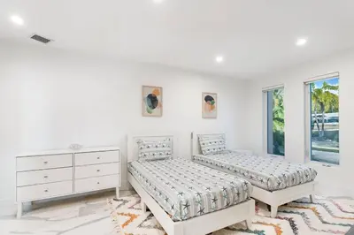 a bedroom with two beds and a dresser and windows at Best Sunset View on the Bay with Pool in Miami Beach