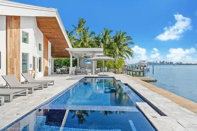 a swimming pool next to a house with the water at Best Sunset View on the Bay with Pool in Miami Beach
