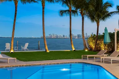 a swimming pool with palm trees and a view of the water at Best Bayfront View Heated Pool in Miami Beach