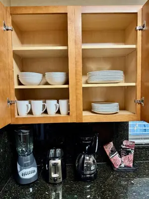a kitchen cabinet with plates and dishes in it at Silver Seas Beach Resort in Fort Lauderdale