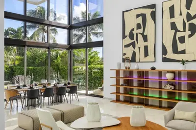 a dining room with a table and chairs and windows at Exquisite Modern Marvel in Golden Isles