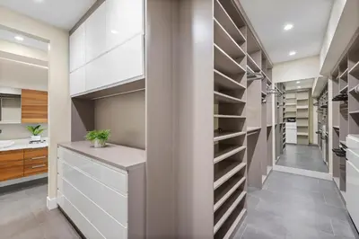 a walk in closet with white cabinets and shelves at Modani Estates in Miami