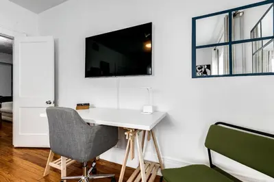 a white desk with a chair and a tv on a wall at Comfy Little Havana Apt - Centrally located Hv2 in Miami