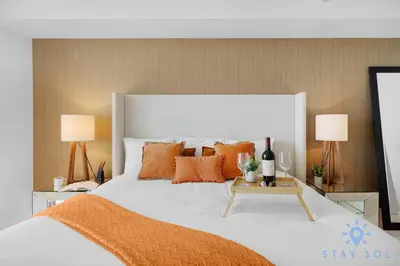 a bed with orange pillows and a table with a bottle of wine at Rooftop Oceanview Balcony Beachfront Resort in Hollywood