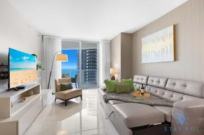 a living room with a sectional couch and a television at Rooftop Oceanview Balcony Beachfront Resort in Hollywood