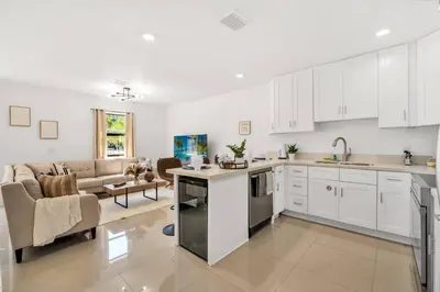 a kitchen with white cabinets and a living room at Urban Seaside in Dania Beach