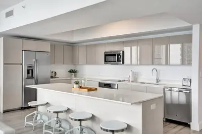 a kitchen with white cabinets and bar stools at Lower Penthouse 3BD 3BA - Beach Pool Gym in Hallandale Beach