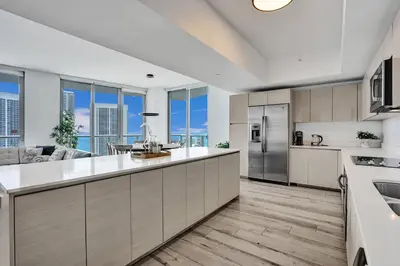 a kitchen with white cabinets and a large kitchen with windows at Lower Penthouse 3BD 3BA - Beach Pool Gym in Hallandale Beach