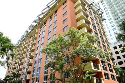 a tall orange building with trees in front of it at 1bed 1bath Steps To Marina & Cocowalk In Grove in Miami