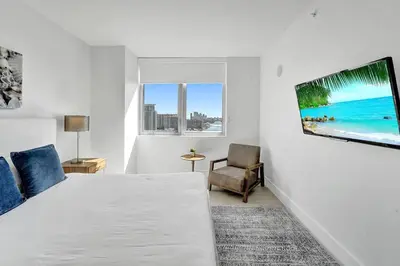 a bedroom with a bed and a tv on a wall at Modern Ocean View 3 Bedroom Condo Resort Amenities in Hallandale Beach