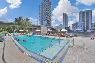 a large swimming pool with people in the water at Modern Ocean View 3 Bedroom Condo Resort Amenities in Hallandale Beach
