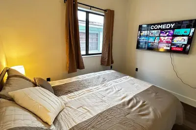 a bedroom with a bed with a tv on the wall at Sunny Delight Home Near Airport in Hollywood