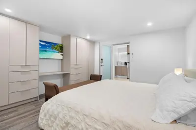 a white bedroom with a bed and a tv at Villa Capri Cottage in the heart of Miami in Miami