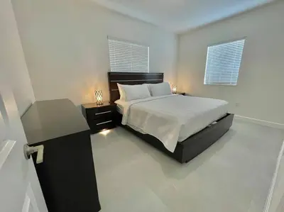 a bedroom with a bed and a table and two windows at Villa Gia Large Home Near Brickell Miami Beach in Miami