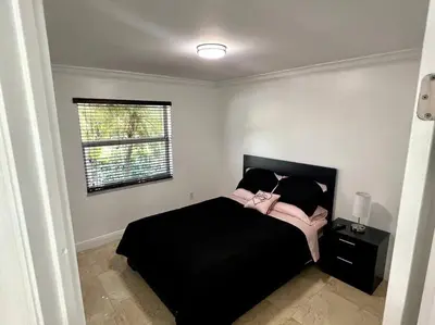 a bedroom with a black bed and a window at Sunny Getaway: Relaxing Miami Home in Tamiami