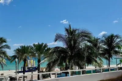 a beach with palm trees and a blue house at 311-22 Beachside in Hollywood