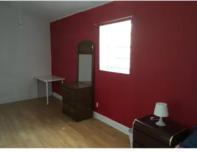 a room with a red wall with a window and a dresser at Miami House in Miami