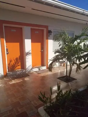 a house with orange doors and a palm tree at Royal Budget Inn in Miami