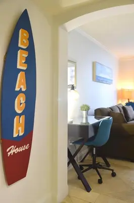 a living room with a surfboard hanging on the wall at Relaxing Condo Hotel In The Grove, Free Parking in Miami