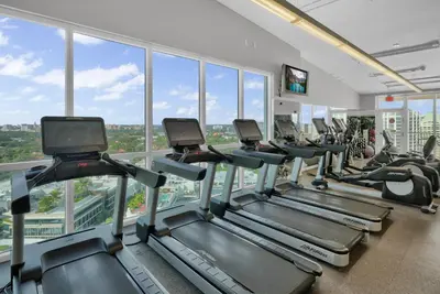 a gym with a row of treadmills and ellipticals at Sight Of Sail Boats! Tranquil 115 Coconut Grove in Miami