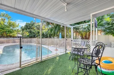 a patio with a table and chairs and a swimming pool at Tranquil Pool Home in Hollywood Close to Beach Airport in Hollywood