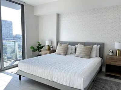 a bedroom with a large white bed with a large window at Miami design district, view of the bay - city in Miami