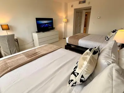 two beds in a room with a tv and a couch at SPECIAL Beautiful Modern Beach Condo in Miami Beach