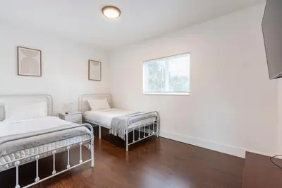 two beds in a white room with a window at Cozy Miami Home Pet-friendly & with Free Parking in Miami