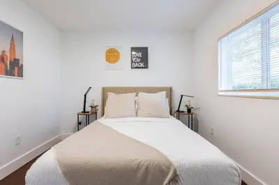 a white bedroom with a large bed with two windows at Cozy Miami Home Pet-friendly & with Free Parking in Miami