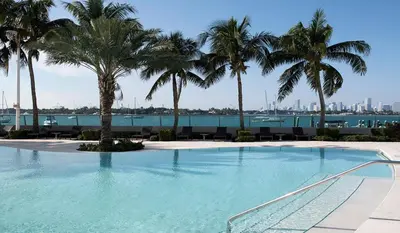 a large swimming pool with palm trees in the background at LUXURY APARTMENT - Direct Bay in South Beach in Miami Beach