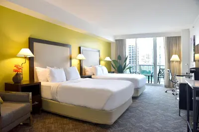 two beds in a hotel room with a balcony at Stunning 12th Floor Studio In The Heart Of Grove in Miami